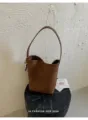 Détail de sac seau en cuir tressé marron, bandoulière simple, style minimaliste quotidien - Avec Pendentif / Marron