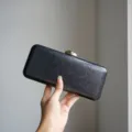 Metallic texture evening clutch detail shot, highlighting exquisite gold clasp and hard case design. - Black