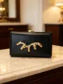 Black hardcase evening clutch bag featuring gold liquid metal and sparkling rhinestone details - Black