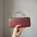 Detailed view of the luxury metal branch handle evening clutch bag showing its exquisite texture. - Burgundy