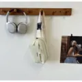 Detailed view of minimalist casual crossbody bag hanging on wall hook, light green. - Alphabet Print Crossbody Bag (57805) / White
