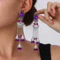 Close-up detail of ethnic vintage silver dangling jhumka earrings with purple crystal stones. - Fan Carved Tassel Bell Style (S5121-3) / Purple