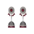 Close-up van zilverkleurige jhumka oorbellen met opengewerkte patronen en rode kralenkwastjes. - Donkerrood