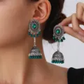 Close-up detail of bohemian hollow bell dangle earrings with green beads and ethnic style. - Green