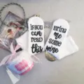 Close-up detail of cozy white fuzzy novelty socks featuring funny text on the soles. - One Size / White