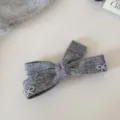 Primo piano della molletta per capelli a fiocco in maglia grigia con perle, elegante accessorio. - Fermaglio a Molla con Perle / Grigio
