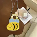 Vue rapprochée du sac téléphone abeille en peluche douce avec corps rayé et visage souriant. - Abeille Jaune