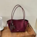 Close-up of the burgundy suede tote bag showing cute elephant charm and metal logo. - With Charm / Burgundy