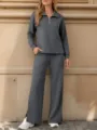 Detail view of the casual dark grey half-zip top and wide leg trousers set worn outdoors. - Dark Gray