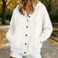 White knit hooded cardigan detail featuring black front buttons and cozy park scene. - White