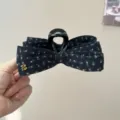 Vue détaillée de la pince à cheveux noire en tissu floral avec un élégant accent doré. - Pince Nœud Floral Noir