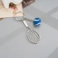 Close-up detail shot of the metal tennis racket keychain with a cute blue fuzzy tennis ball. - Alloy Tennis Racket Pendant (K6724) / Blue