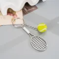 Detail shot of a stylish metal tennis racket keychain with a mini tennis ball pendant, charm. - Green