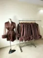 Detailed view of satin robe with sheer mesh sleeves and ruffled cuffs in indoor showroom. - US4 / Robe / Coffee