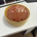Detailansicht von süßem Glitzer Brötchen Quetschspielzeug im Dämpferkorb auf dem Bürotisch. - Bronze