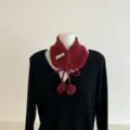 Vue détaillée du col en tricot d'hiver chaud avec jolis liens à pompons et étiquette. - Rouge