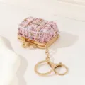 Detailaufnahme des rosa Tweed Mini Tasche Anhängers mit goldenem Metallbügel und Schlüsselring. - Rosa