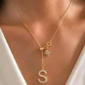 Primer plano detallado de un delicado collar chapado en oro con colgantes de letras. - Letra S