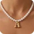 Detalle en primer plano del elegante collar de perles con colgante de letra A de oro. - Letra A