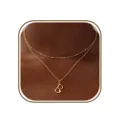 Primer plano detallado de un collar dorado de doble capa con un colgante de letra B elegante. - Letra B