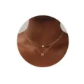 Primer plano detallado de un collar dorado doble minimalista con dijes de corazón y letra M. - Letra M