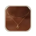 Detailopname van een minimalistische gouden dubbellaags ketting met elegante N-letterhanger. - Letter N