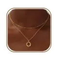 Gedetailleerde close-up van een dubbellaags gouden ketting met fijn kralenketting en hanger. - Letter Q