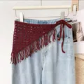 Detailed view of the dark red knitted crochet triangle scarf with fringe and tie straps. - One Size / Burgundy Fringe