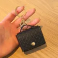 Close-up detail van een stijlvolle zwarte gewatteerde PU mini tas met gouden sleutelhanger. - Zwart