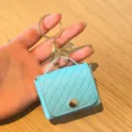 Lichtblauwe gewatteerde PU mini tas sleutelhanger en oordopjeshoesje met gouden hardware. - Blauw
