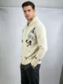 Dettaglio in primo piano di un cardigan in maglia da uomo con motivo animale distintivo. - Champagne