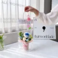 Handmade crochet blue rose flower bouquet in a clear gift bag detail scene display. - Holding Bucket + Gift Bag Card / Blue and White Rose