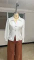 Detailed view of white long sleeve blouse featuring lapel collar and golden metal buttons. - Color 13