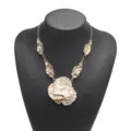 Detailed shot of the exaggerated layered flower pendant necklace with metallic leaf accents. - White