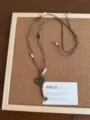Primo piano dettagliato della collana con ciondolo chiave a cuore, corda intrecciata e perle. - Collana Chiave a Cuore (XL5938A)