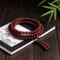 Vue en gros plan détaillée d'un bracelet en perles de bois sur un livre classique. - Coupe régulière / 8mm*108 Perles