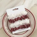 Gedetailleerde close-up van satijnen haarscrunchies set in wit en bruin op presentatiekaart. - Gebroken Wit en Koffie