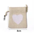 Close-up detail view of the rustic burlap drawstring pouch featuring a white heart print. - 8x10cm / Beige-Gray Heart