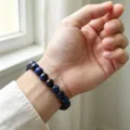 Gros plan d'un bracelet de perles en pierres gemmes bleues naturelles porté au poignet. - Bracelet Oeil de Tigre Doré 8mm