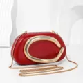 Red leather evening clutch bag with metal chain strap and metallic C clasp design. - Red