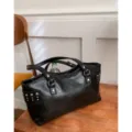 Bolso tote negro brillante con tachuelas plateadas y dos asas, colocado sobre una mesa de madera - Sin colgante / Negro