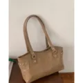 Bolso tote color topo de cuero sintético, con dos asas y tachuelas plateadas, mostrado de pie - Sin colgante / Caqui