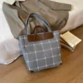 Graue karierte Stofftasche mit braunen Kunstledergriffen und verstärkten Ecken, aufrecht gezeigt - 30*15*33cm / Grau