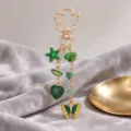 Gold-tone charm with green starfish, heart, butterfly, and stone beads, displayed on draped fabric - Green Starfish & Stone Style (ZJ17292)