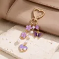 Close-up of purple enamel flowers, butterfly and pearl-accented heart charms on a gold-tone clasp - Purple Enamel Butterfly & Artificial Pearl Style (ZJ17293)
