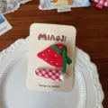 Detalle de una pinza de fresa con lazo verde y perlas junto a otra pinza de tela a cuadros - Estilo de Fresa / Combinación (Clips BB)