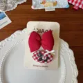 Primer plano de un lazo rojo de tela y una pinza vichy roja y blanca con motivo negro y cinta blanca - Estilo de Lazo Acolchado / Lazo + Clip BB Ovalado