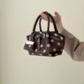 Brown polka dot bucket handbag with matte fabric, dark leather handles and metal buckle detail - Coffee Brown