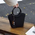 Black woven bucket handbag with a circular top handle, shoulder strap clips and wooden bead tassel - With Pendant / Black