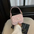 Petit sac rose à pois, avec fermoir papillon et bandoulière chaîne dorée, présenté à la main - Rose